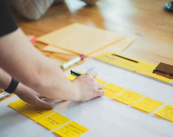 A person writing on yellow post-it notes. 