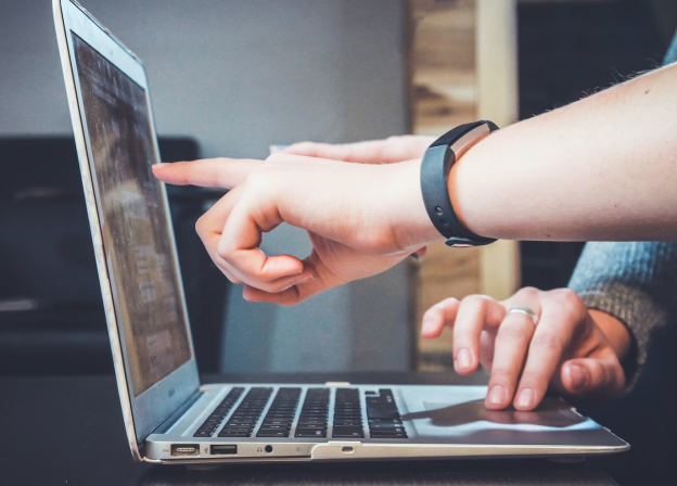 Two people sitting at a computer talking.