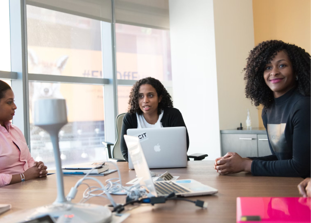 Three women sitting and talking at a conference table.